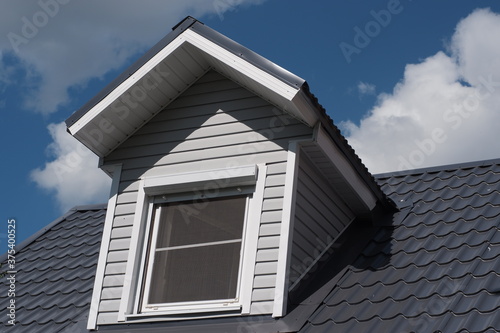 Gray roof of the house against the blue sky. The roof is made of metal.