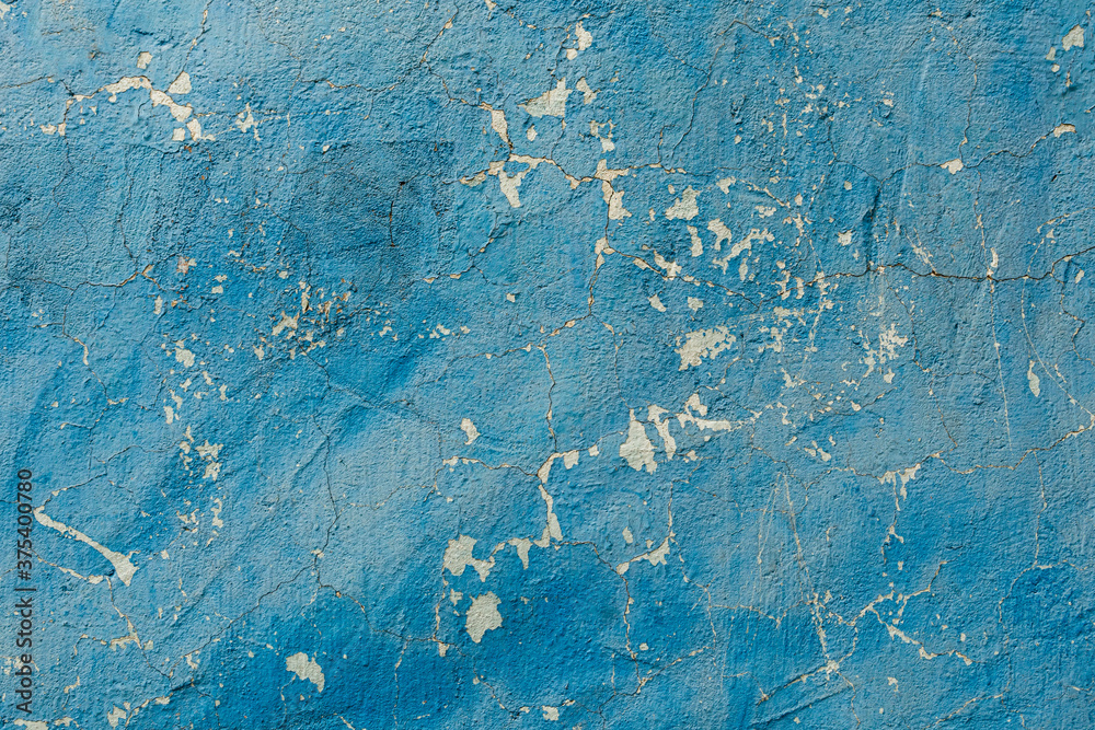Old cracked blue wall as background. In some places, paint has fallen off and plaster is visible