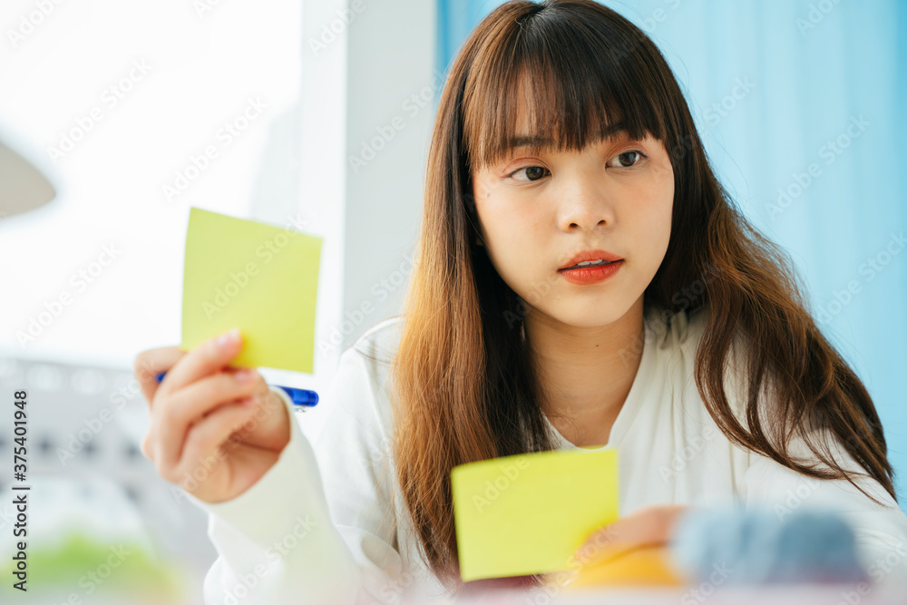 Asian dark hair woman writing and planning works on sticky note paper. Asian dark hair woman writing and planning works on sticky note paper.