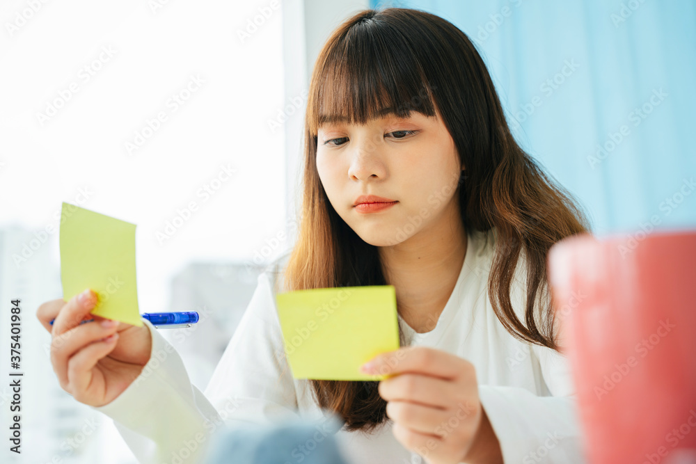 Asian dark hair woman writing and planning works on sticky note paper. Asian dark hair woman writing and planning works on sticky note paper.