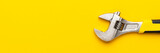 Minimalist photo of adjustable wrench with copy space. Adjustable wrench with yellow handle on the yellow background.