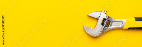 Minimalist photo of adjustable wrench with copy space. Adjustable wrench with yellow handle on the yellow background. photo