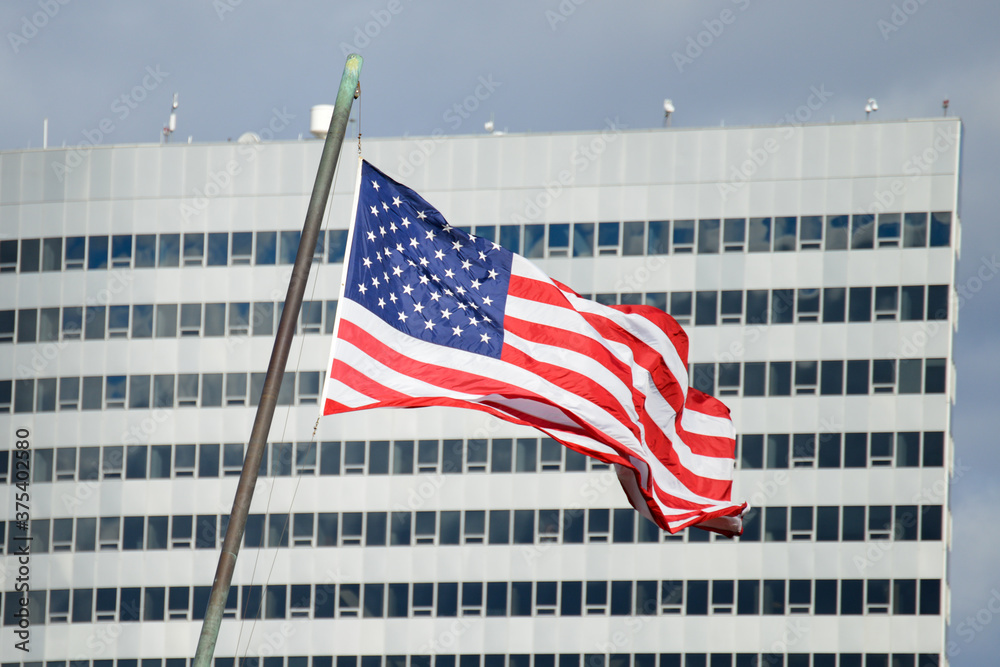 American flag with a corporate building background