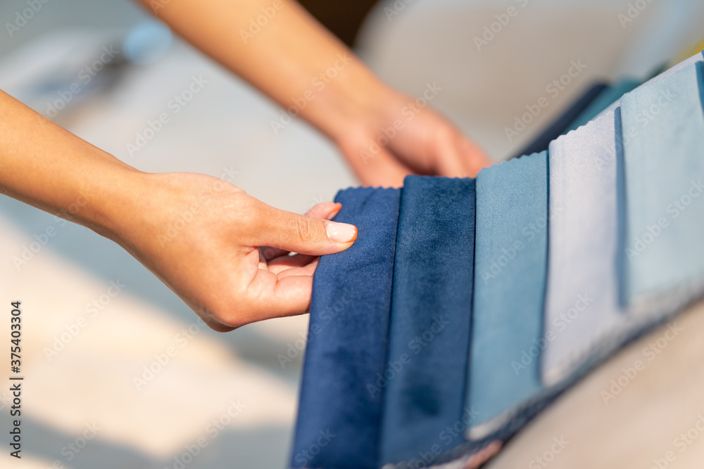 The woman chooses the fabric on the sofa. Textile industry background. Tissue catalog The woman chooses the fabric on the sofa. Textile industry background. Tissue catalog