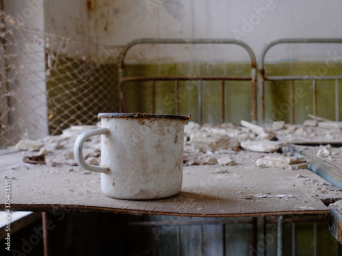 A white metal mug on a bed in an abandoned building in Chernobyl. © Oleksii