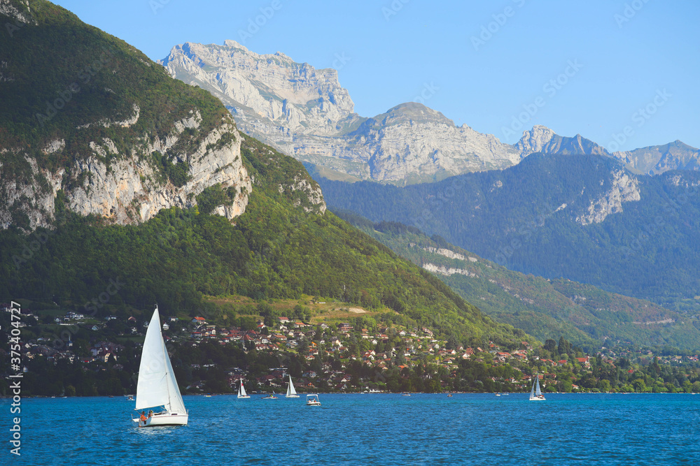 Naklejka premium View of Annecy lake with clear turquoise water, sailing boats and traditional wooden houses in summer day, France