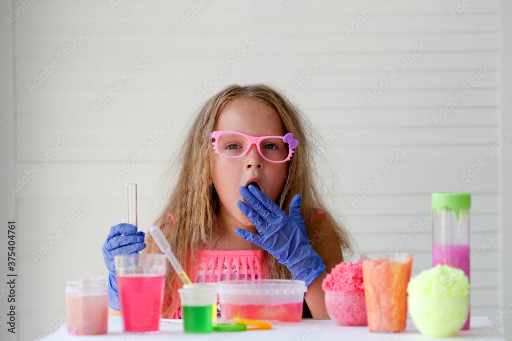 A little girl in pink glasses conducts experiments, looks at the camera . A child in rubber gloves takes a liquid with a pipette and adds it to the test tube. A little girl in pink glasses conducts experiments, looks at the camera . A child in rubber gloves takes a liquid with a pipette and adds it to the test tube.