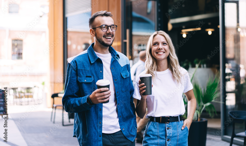 Young 20s caucasian male and female couple in love enjoying date talking to each other and holding coffee to go cup, cheerful woman and man friend resting and communicating on leisure weekends
