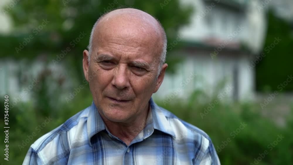 portrait of an old Caucasian man sad against the background of a garden portrait of an old Caucasian man sad against the background of a garden