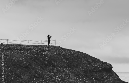 Photographer alone on top of a hill photographing the sea