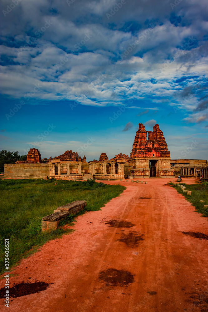 vithala temple with leading red soil road and amazing blue sky at hampi ruins