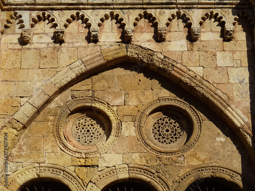 Cathedral of Tarragona. Spain. 12-13 century. 
Detail of the cloister. Cornice decorated with multifoil arches, brackets with heads and lattice in the rose window.   photo