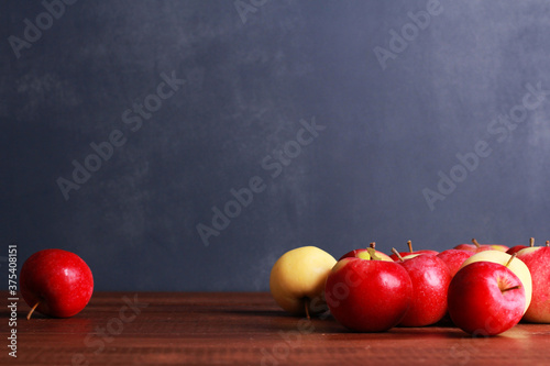 Red ripe apples on brown wooden table against dark blue wall background with copy space. Natural organic food, healthy eating, harvest season concept