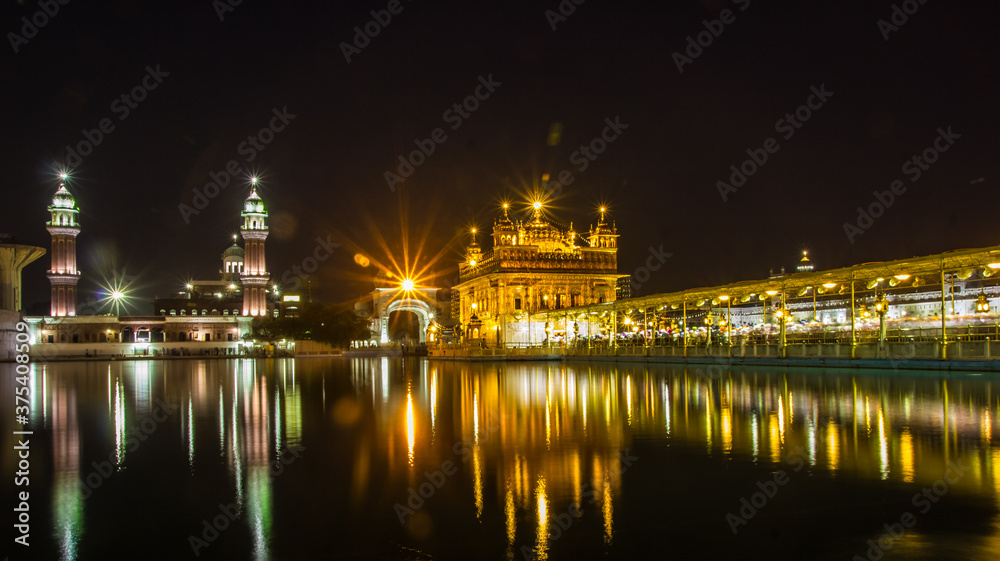 reflection of golden temple at night on water surface of nearby lake