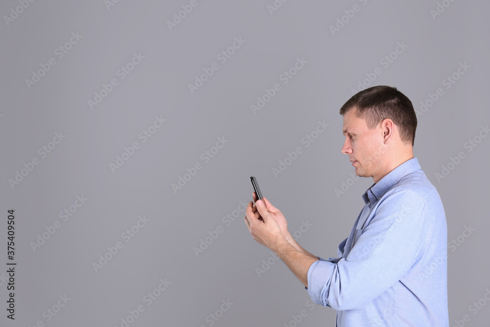 Man unlocking smartphone with facial scanner on grey background, space for text. Biometric verification Man unlocking smartphone with facial scanner on grey background, space for text. Biometric verification