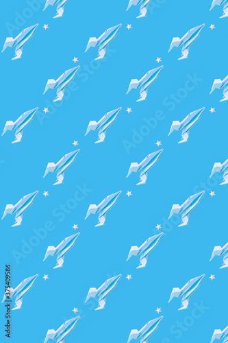 Paper origami rocket flies among paper stars on a blue background, pattern. Space concept. International Day of Human Space Flight, Cosmonautics Day.