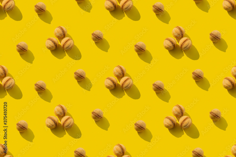A repeating pattern of walnut cookies on a yellow background. Seamless texture A repeating pattern of walnut cookies on a yellow background. Seamless texture