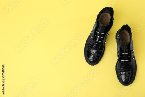 Pair of stylish ankle boots on yellow background  top view. Space for text