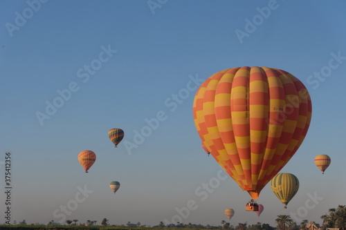Early morning hot air balloon in flight over vast plain with trees