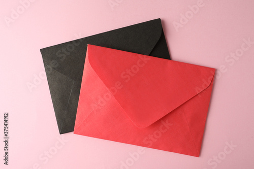 Colorful paper envelopes on pink background, top view