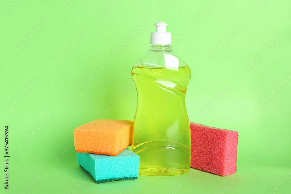 Bottle of detergent and sponges on green background Bottle of detergent and sponges on green background