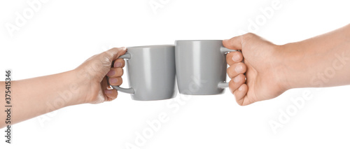Obraz na plátne Women clinking light grey cups on white background, closeup