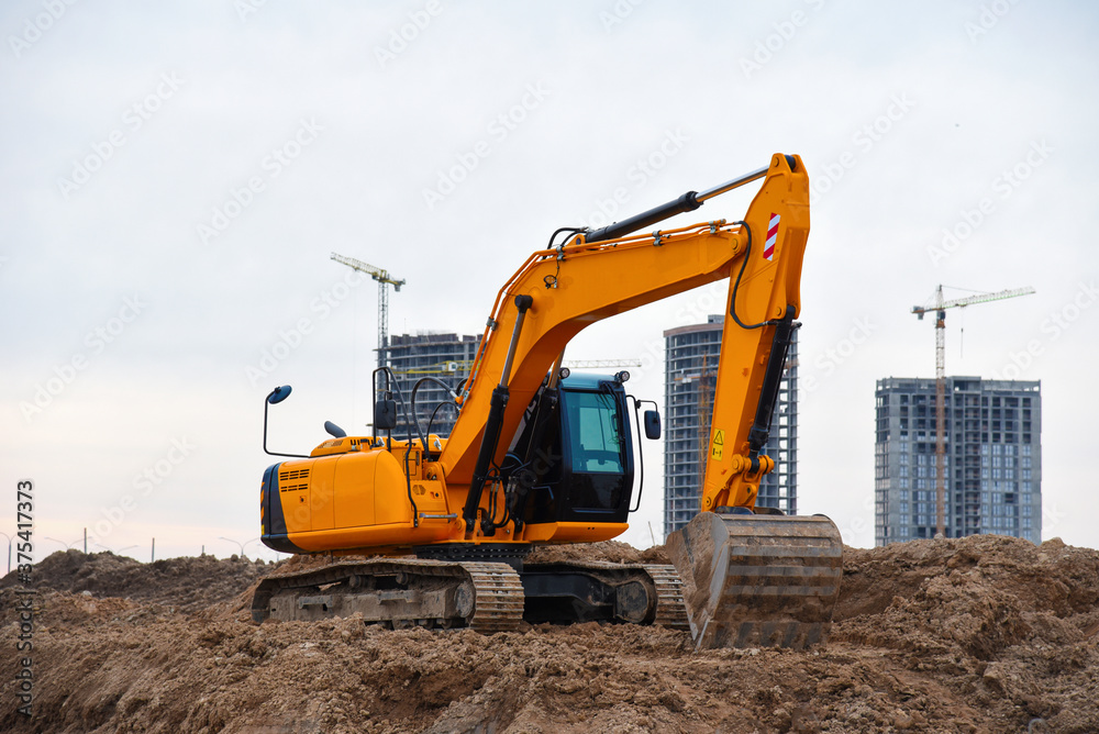 Excavators during earthworks at construction site. Backhoe the digging pit for construct building foundation. Paving out sewer line. Construction machinery for excavating, loading, lifting and hauling Excavators during earthworks at construction site. Backhoe the digging pit for construct building foundation. Paving out sewer line. Construction machinery for excavating, loading, lifting and hauling
