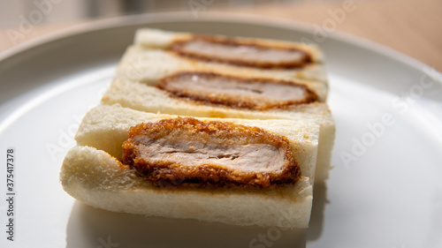 Pork cutlet tonkatsu sandwich or katsu sando is a popular convenient snack food in Japan found in stores, subway and mall markets sometimes packaged in wooden boxes. Close-up selective focus on plate. (ID: 375417378)