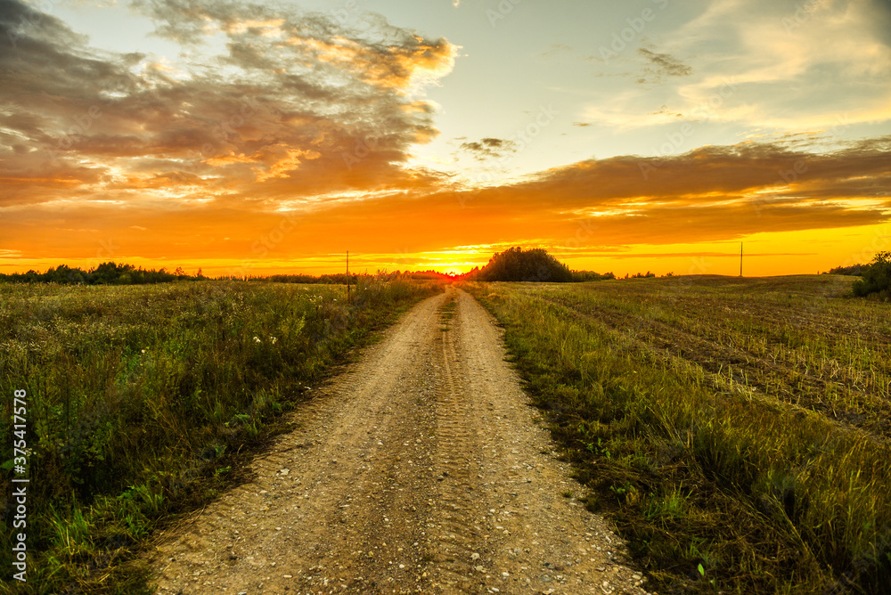Sunset or sunrise and the road through the field. Photo under retro style