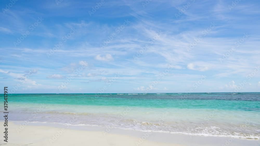 Turquoise sea waves on the white sand of a Caribbean beach. Blue cloudy sky on a sunny summer day over the Atlantic. Blue ocean background. Turquoise sea waves on the white sand of a Caribbean beach. Blue cloudy sky on a sunny summer day over the Atlantic. Blue ocean background.