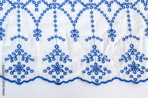 Blue embroidered on white ladies summer blouse on white surface.