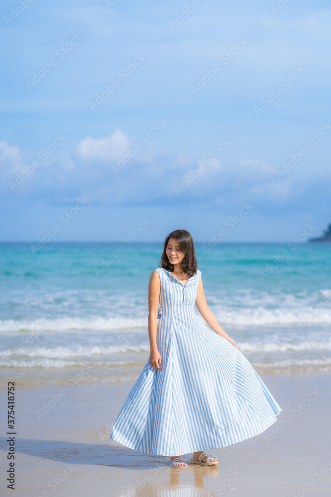 Full length of happy woman in beautiful blue summer dress posing and enjoying a walk on the sea beach with blue sky horizon, vacation and travel ocean concept. Phuket, Thailand. Full length of happy woman in beautiful blue summer dress posing and enjoying a walk on the sea beach with blue sky horizon, vacation and travel ocean concept. Phuket, Thailand.