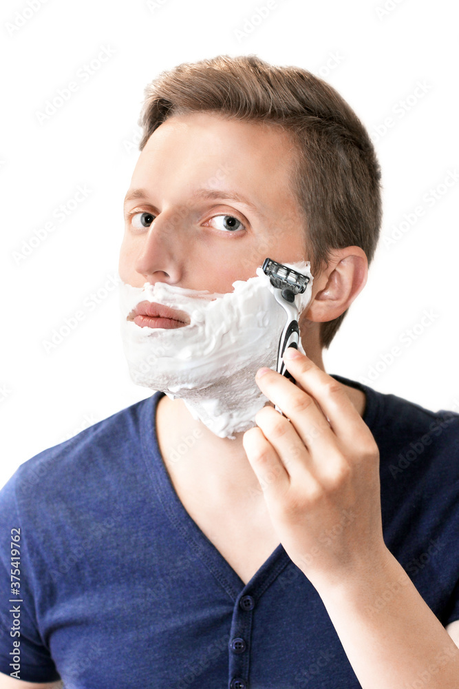 The guy shaves on a white background. Facial care. Razor and foam The guy shaves on a white background. Facial care. Razor and foam