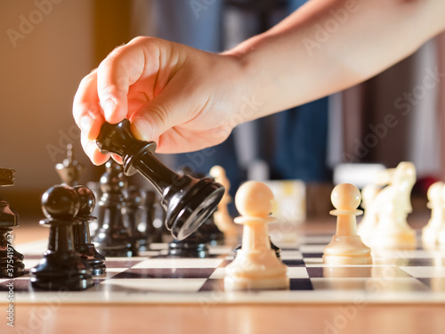 Girl's hand moving chess piece. 