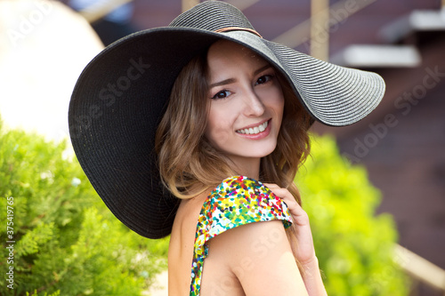 Smiling woman in fashionable look. Woman in straw hat and colorful dress. Summer time