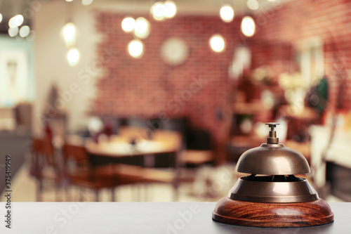 Grey stone table with hotel service bell on blurred background. Space for text