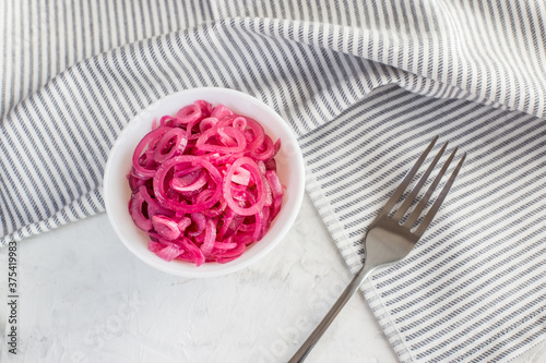 Juicy red onion marinated in lemon juice on a light background.