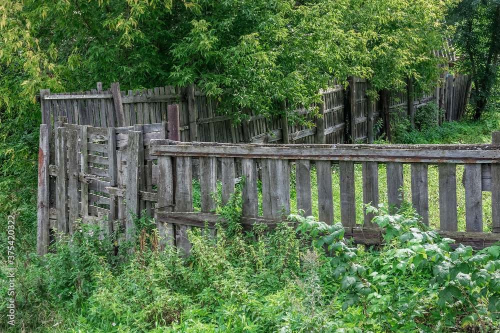 old wooden fence in an abandoned village garden in the summer