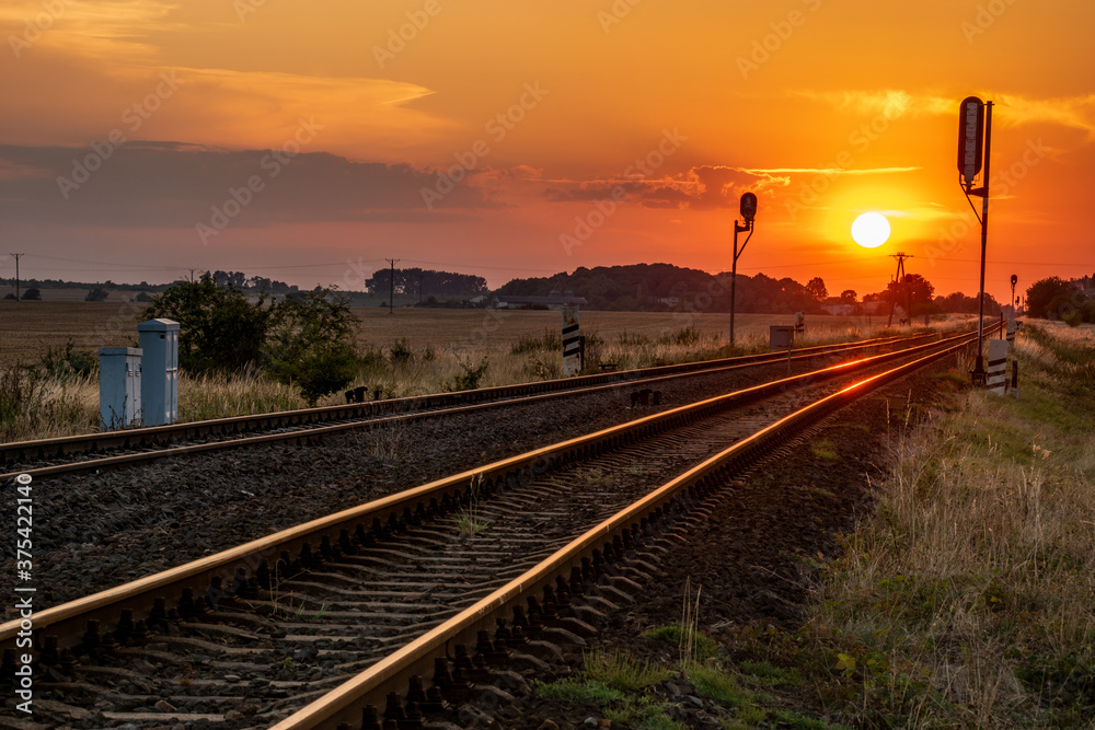 sun is setting over the railroad tracks - obrazy, fototapety, plakaty 