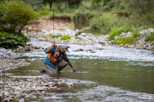 Fototapeta Naklejka Na Ścianę i Meble -  A fly fisherman fishing a trouts in mountain river