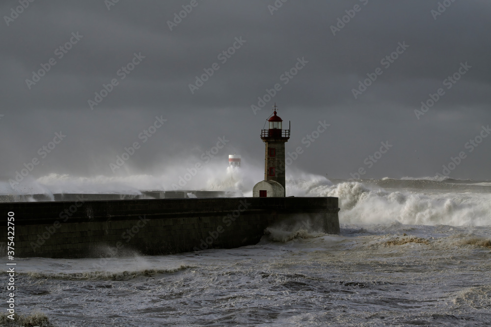 Stormy waves over piers and lighthouse