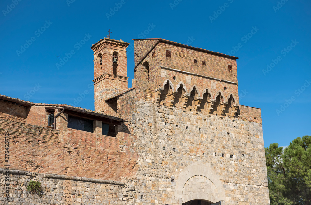 Fragment of the fortress wall with a defensive tower and bell tower in San Gimignano, Italy
