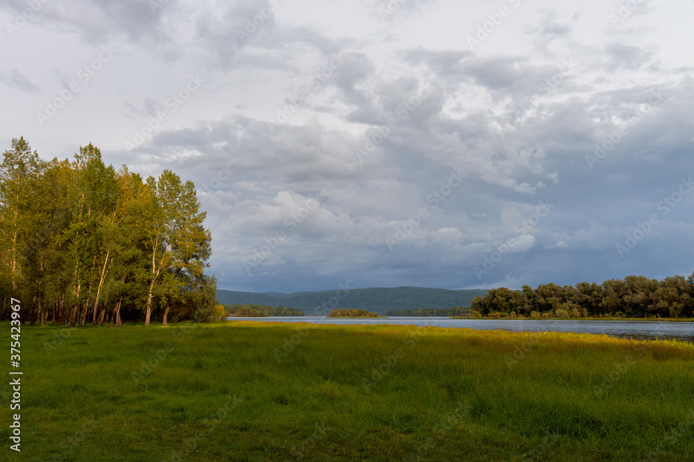 Obraz premium The rays of the setting sun glide along the bank of the Yenisei, on the beginners to paint with autumn colors of grass and trees.