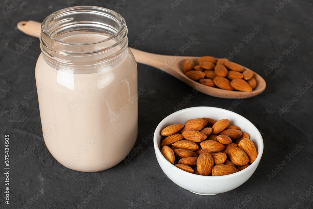 Almond milk in glass with almonds on concrete background Almond milk in glass with almonds on concrete background