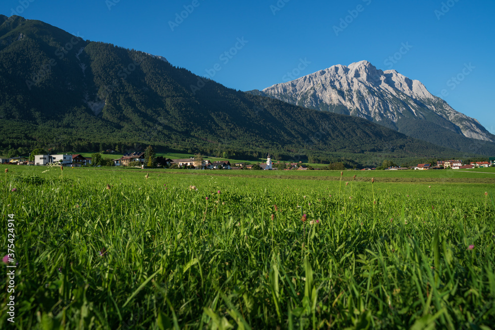 Panoramic view on traditional Austrian village with alpine rocky mountain range background, Wildermieming, Mieminger Plateau, Tirol, Austria Panoramic view on traditional Austrian village with alpine rocky mountain range background, Wildermieming, Mieminger Plateau, Tirol, Austria