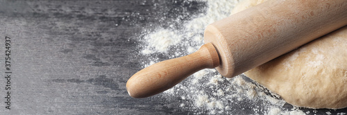Foto Dough with rolling pin and flour on table, closeup