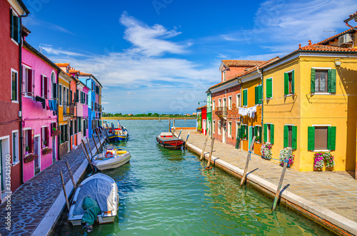 Burano island with colorful houses and buildings on embankment of narrow water canal with fishing boats and view of Venetian Lagoon, Province of Venice, Veneto Region, Northern Italy. Burano postcard