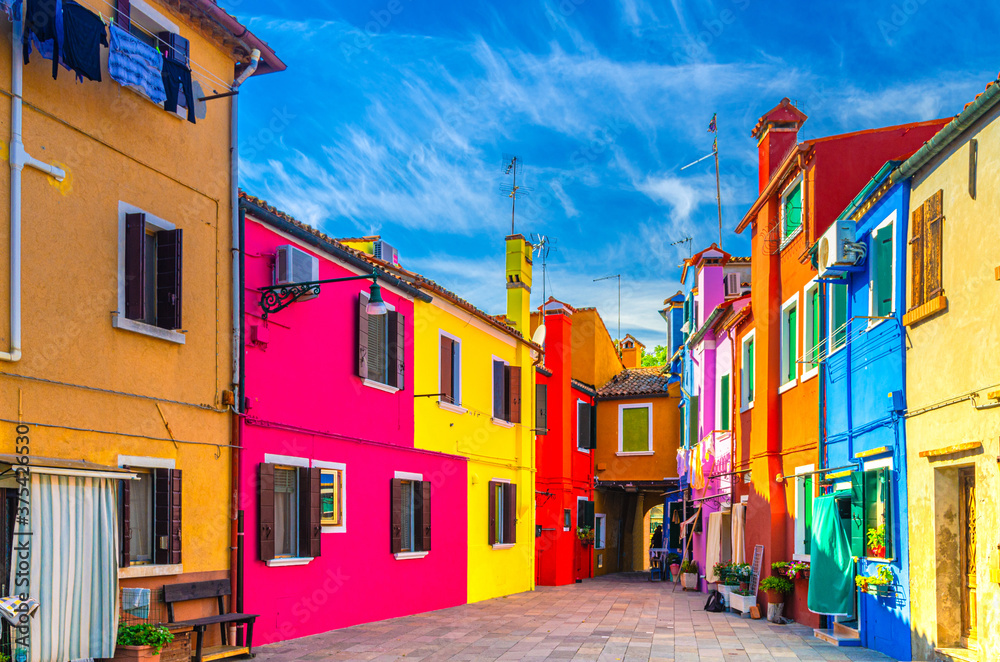 Colorful houses of Burano island. Multicolored buildings in small yard, blue sky background in sunny summer day, Venice Province, Veneto Region, Northern Italy. Burano postcard
