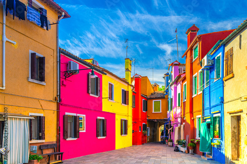 Colorful houses of Burano island. Multicolored buildings in small yard, blue sky background in sunny summer day, Venice Province, Veneto Region, Northern Italy. Burano postcard © Aliaksandr