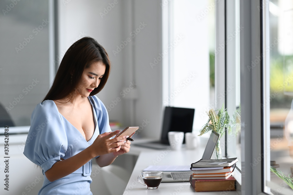 Beautiful woman is using a mobile phone in modern office.